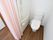 居室の一角に清潔感のあるトイレが設置されている。トイレと居室の床は一続きになっており、カーテンで仕切ることができる。