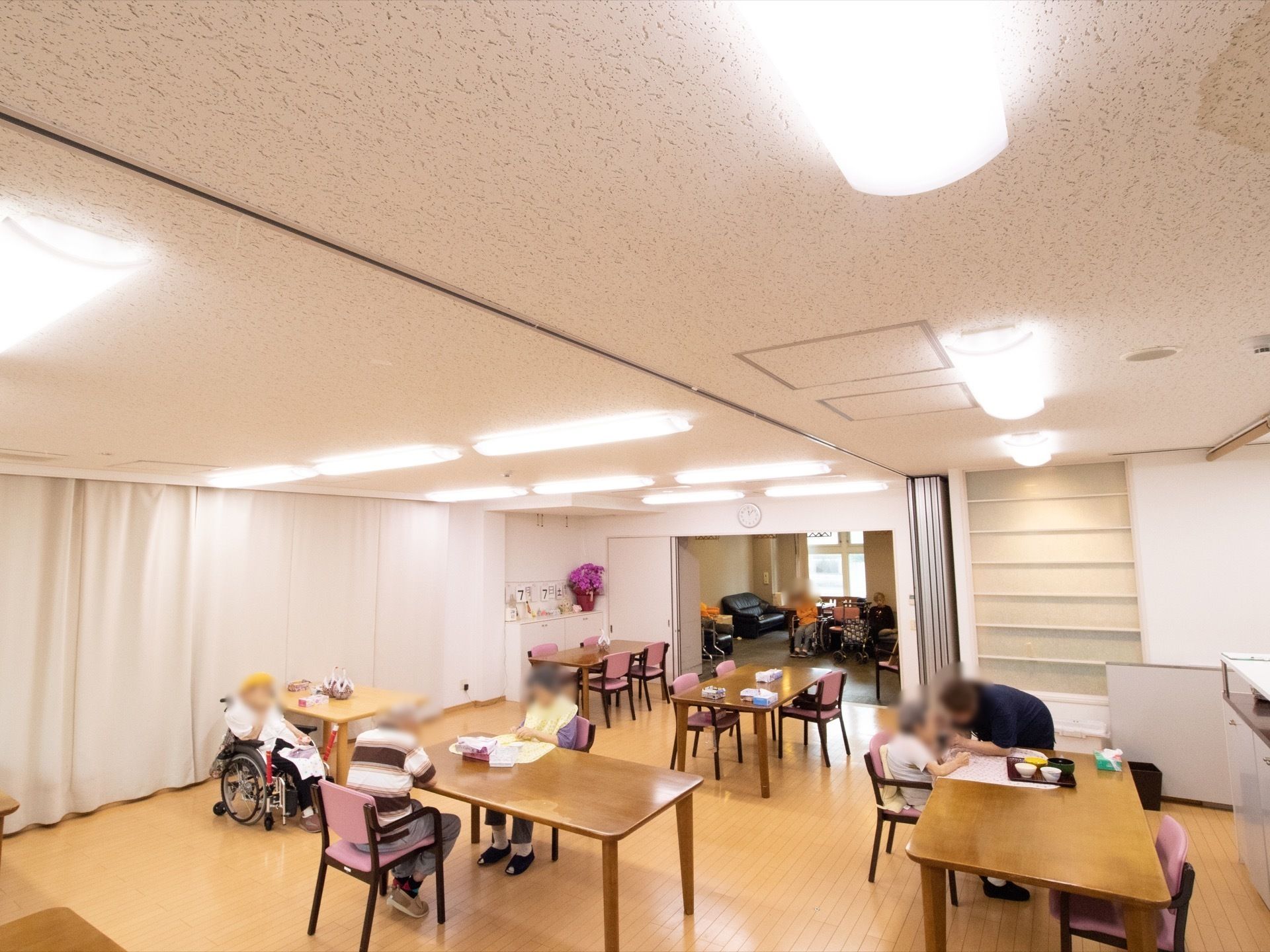 いくつもテーブルが置かれて、食事をしている人やくつろいでいる人のリビング