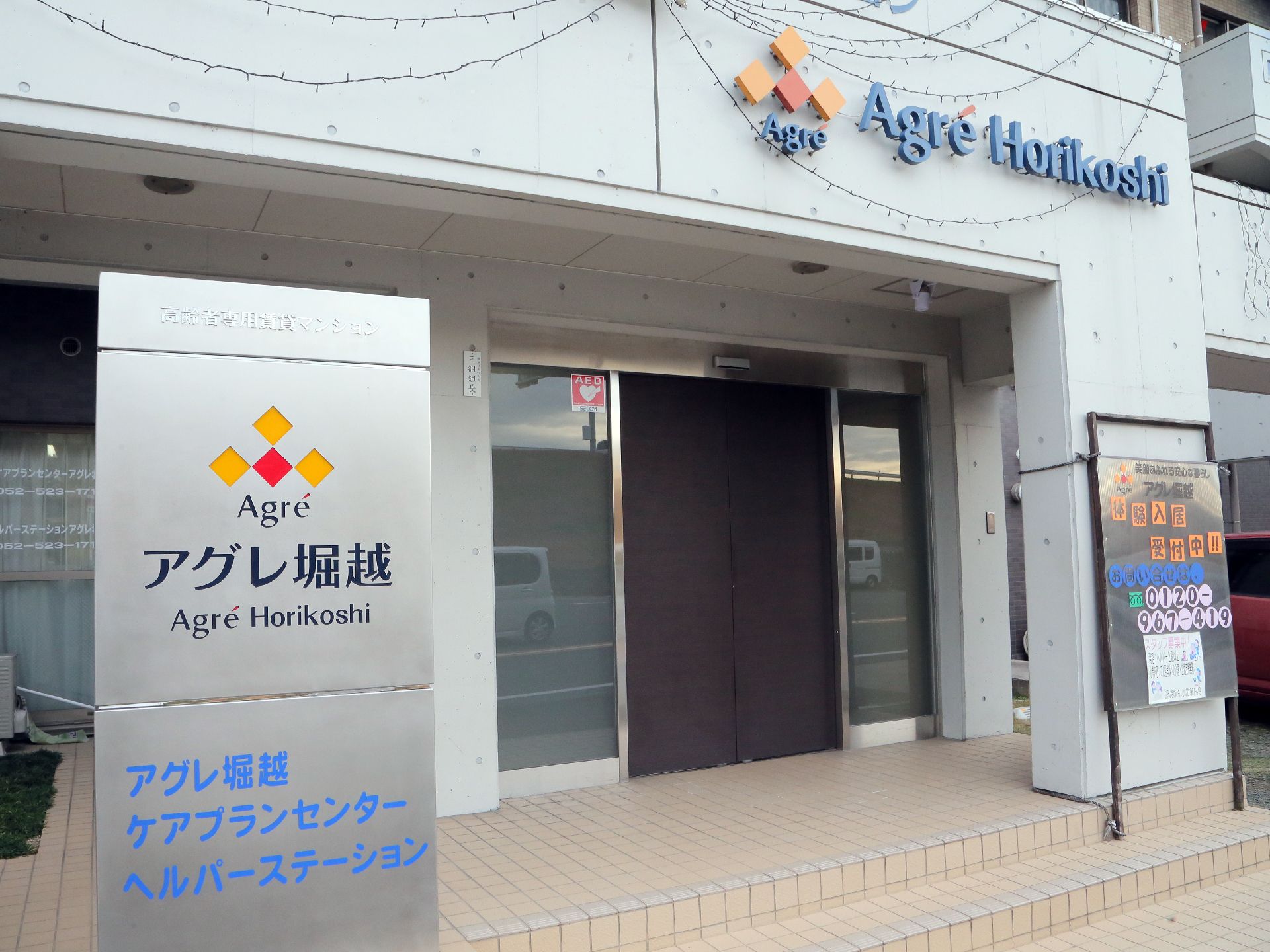 重みのあるブラウンの扉。両脇にはガラス窓が設置されていて、館内は明るくなっています。施設名の看板は解り易い場所へ配置しています。