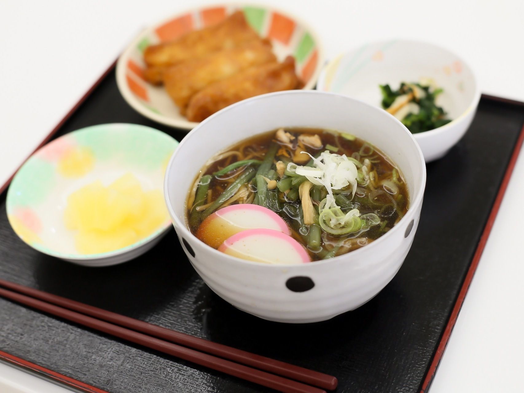 毎日の食事は１人分ずつトレイに乗せられて提供される。山菜そばと小鉢、小皿にいなりずしが３つ並べられている。