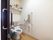 温水洗浄便座機能付きのトイレが設置されている。横の壁には手すりとペーパーホルダー、緊急通報装置が取りつけられている。