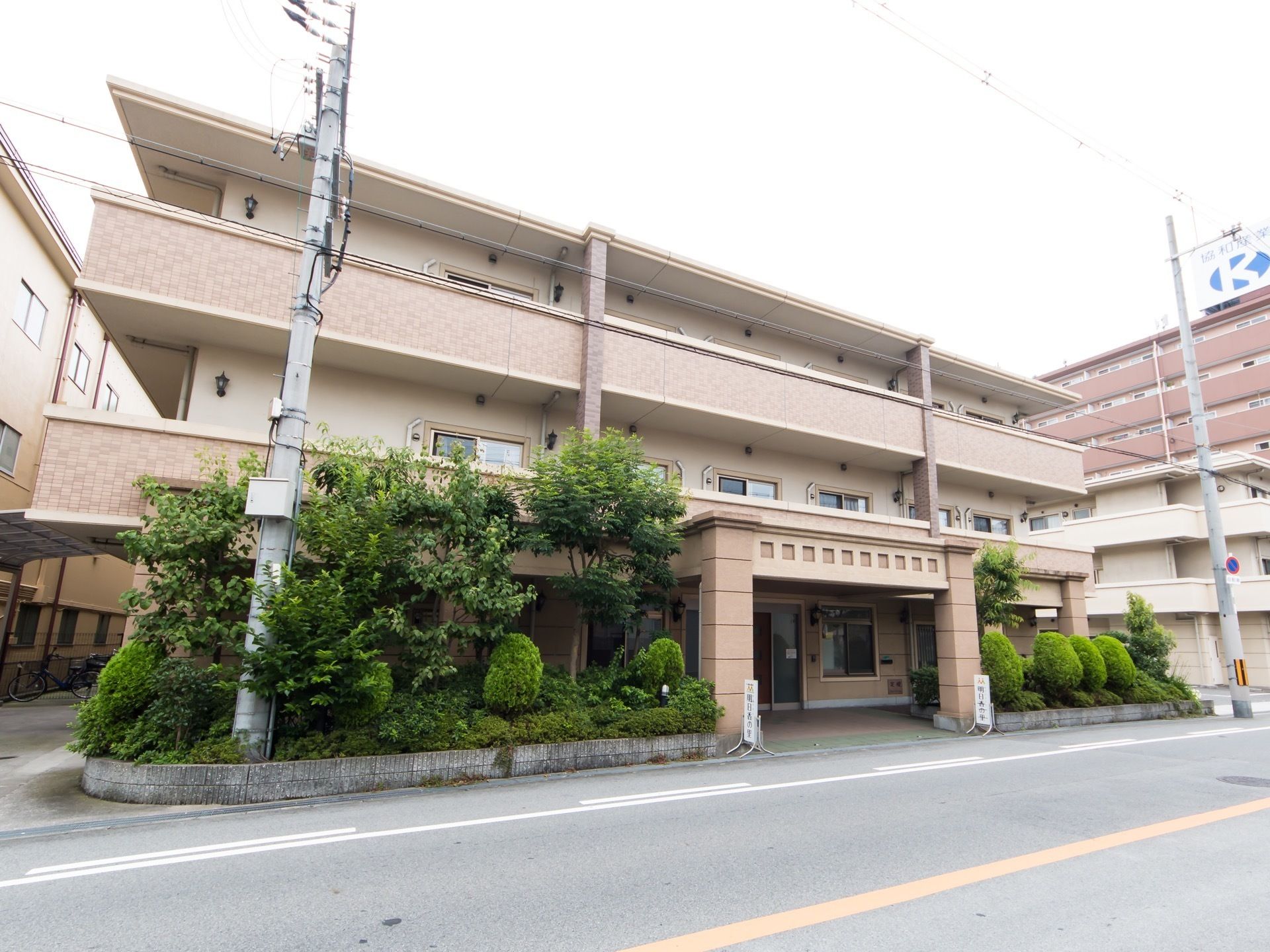 ３階建ての四角い建物。１階中央部に玄関があり、両横に低木と高木を組み合わせた植栽が施されている。２階と3階にはベランダが設けられている。