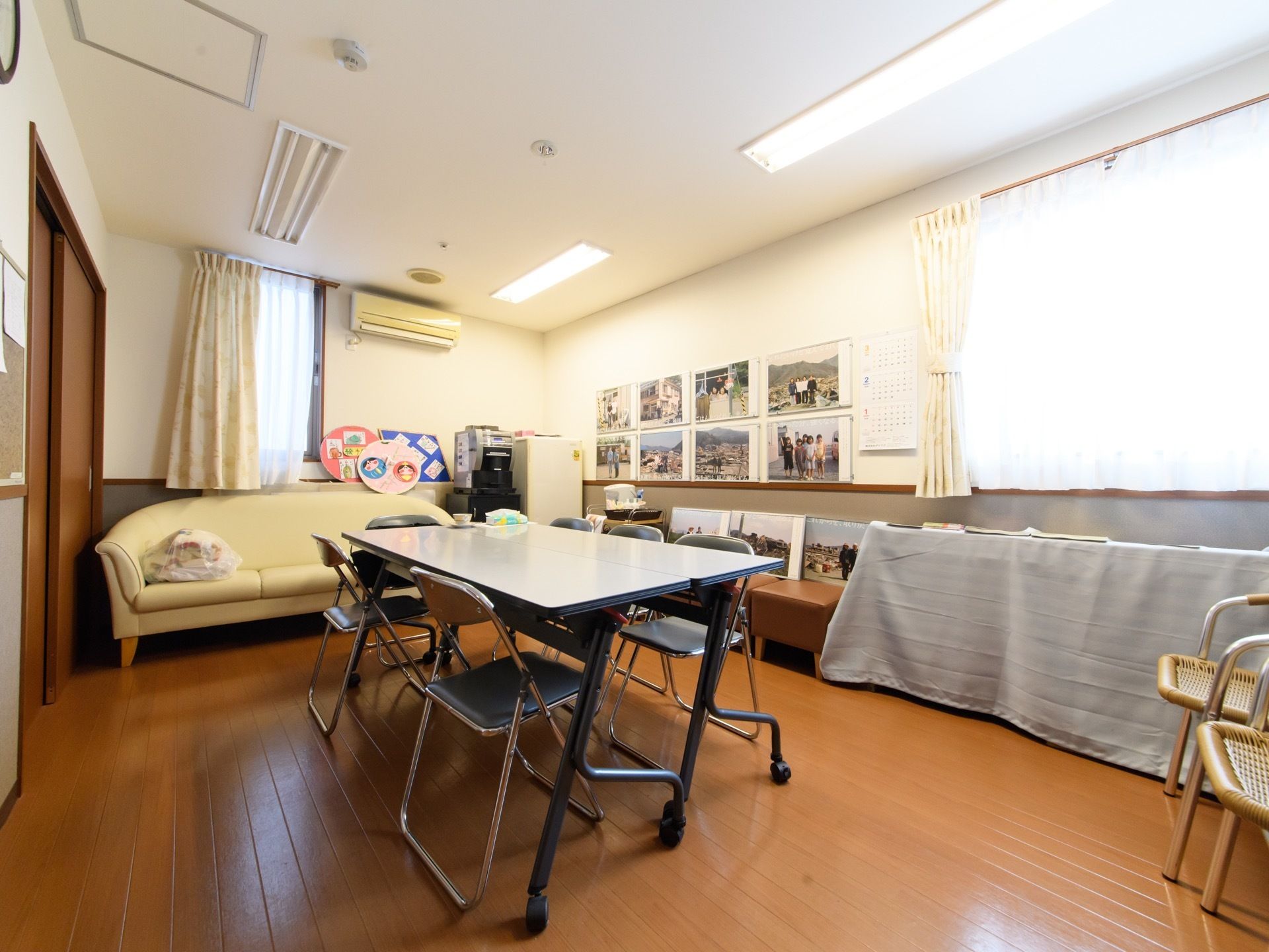 談話室には長テーブルが2つくっつけられた状態で置かれている。周りにはパイプ椅子が6脚並べられている。近くにはソファーがある。
