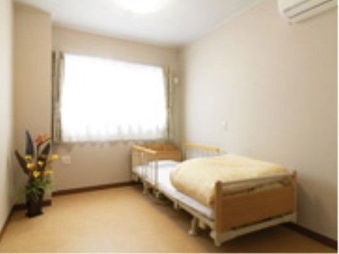 窓から自然光の入るベッドやエアコンが設置された居室