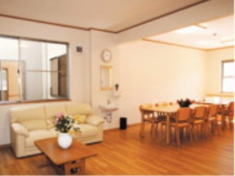 テーブルセットと白いソファーや花瓶に飾られた花が設置された共有スペース