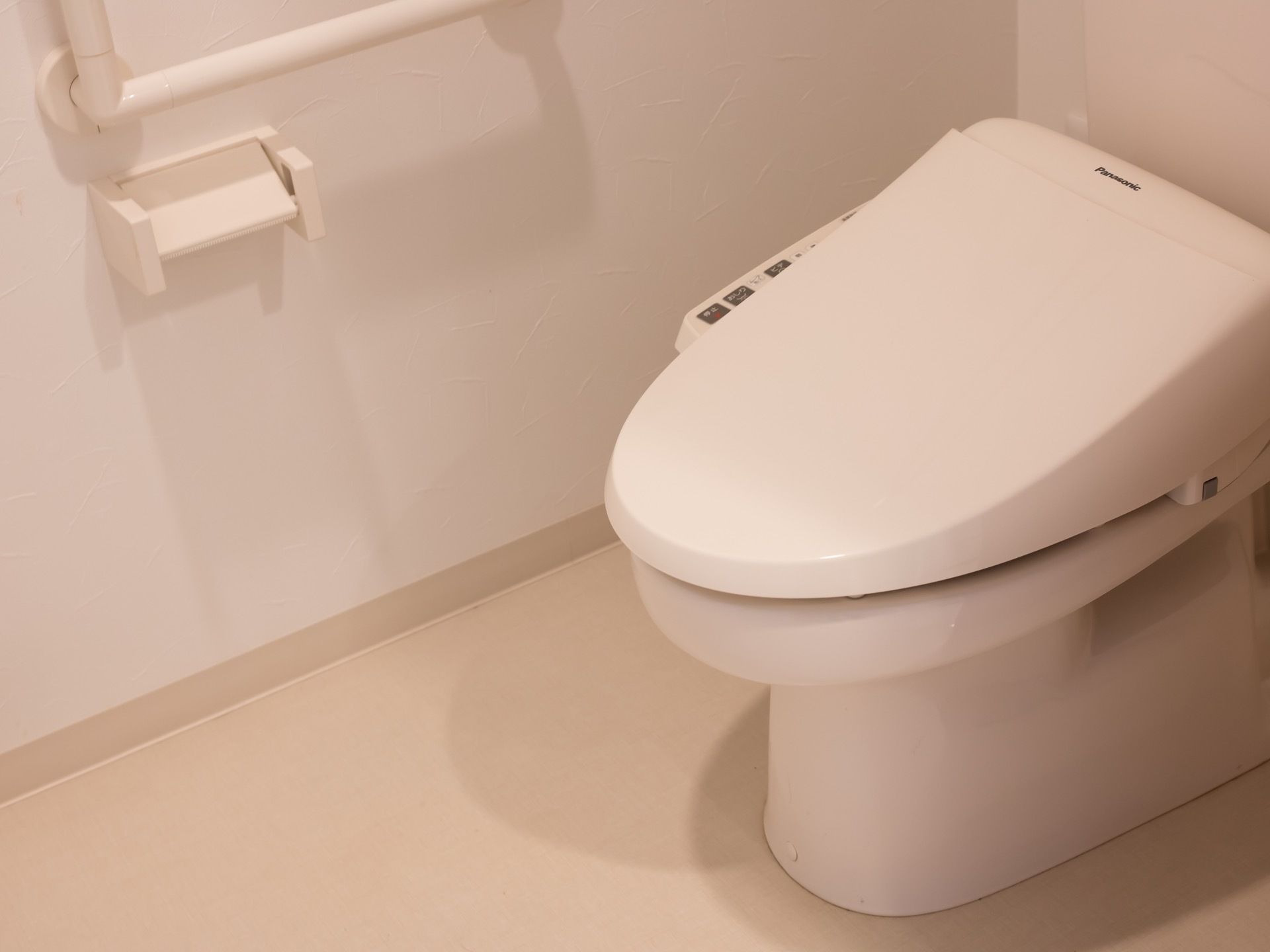 洗浄機付きのトイレが設置されている。トイレットペーパーホルダーの上部には手すりが取り付けられている。