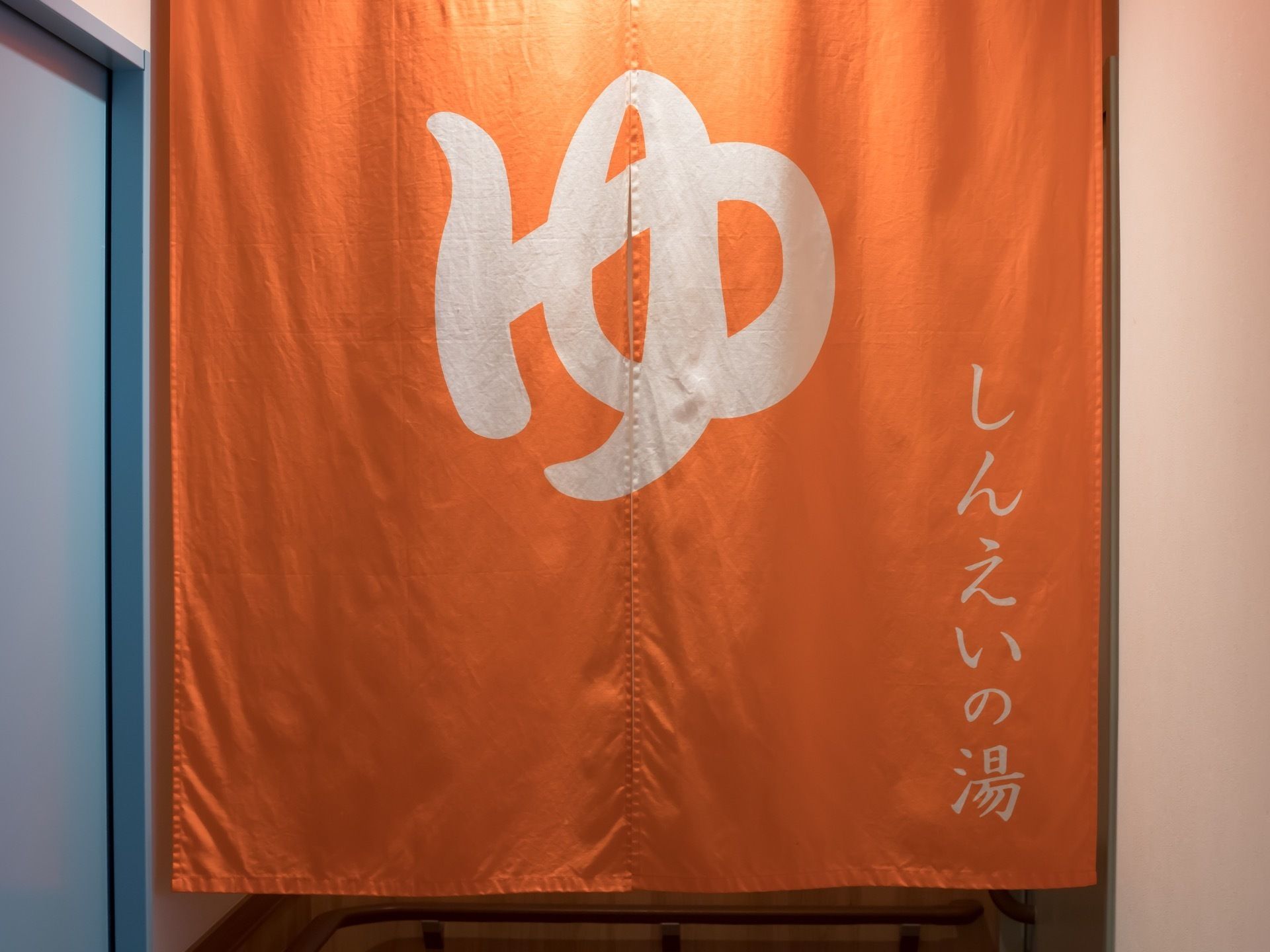 浴室へと続く通路の入口には橙色ののれんが掛かっており、中央に「ゆ」と大きく記載している。のれんの先の通路には手すりが備え付けられている。