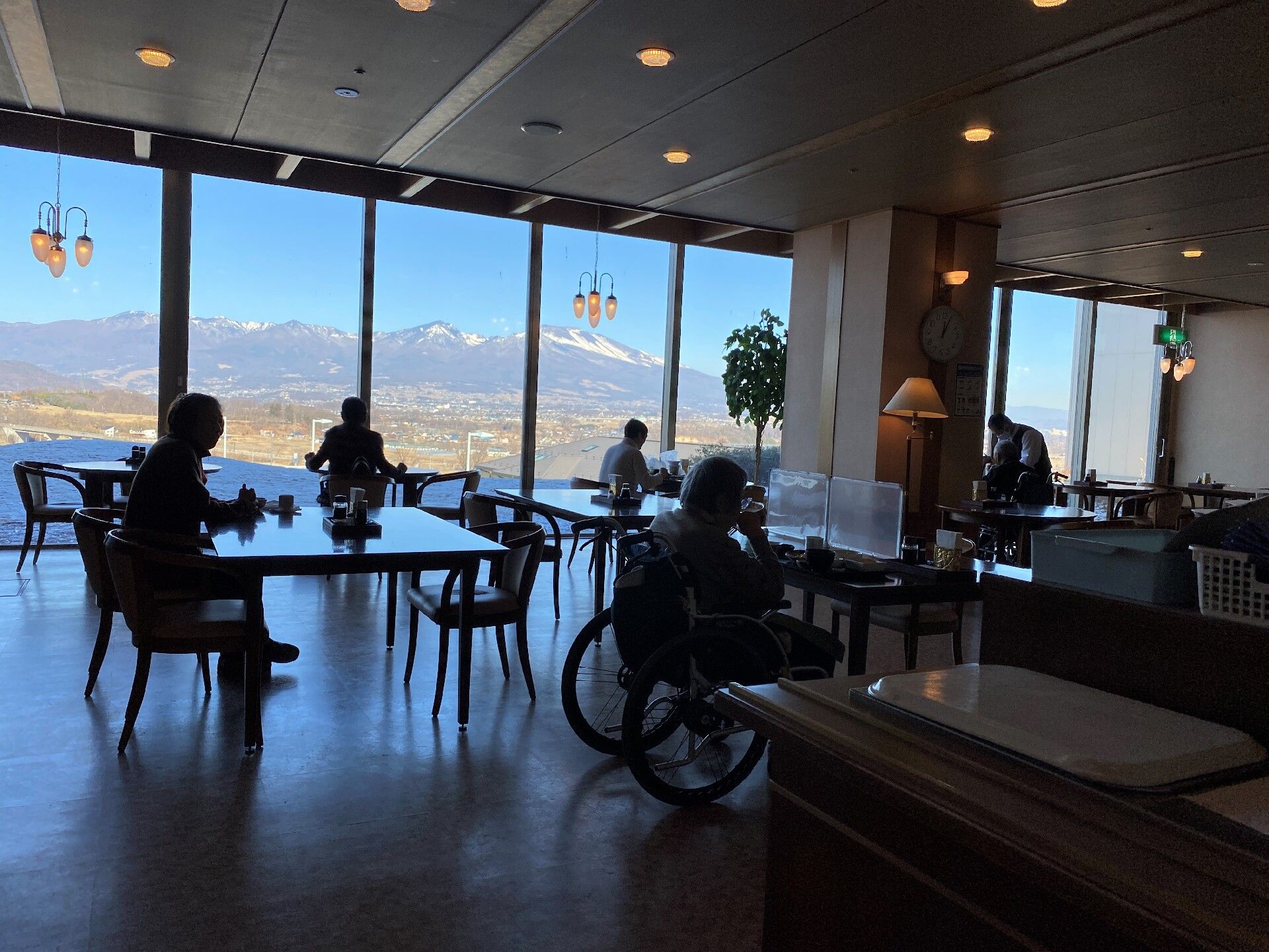 奥の窓からは、山々が見えご入居者様が椅子に座っている食堂から見える景色
