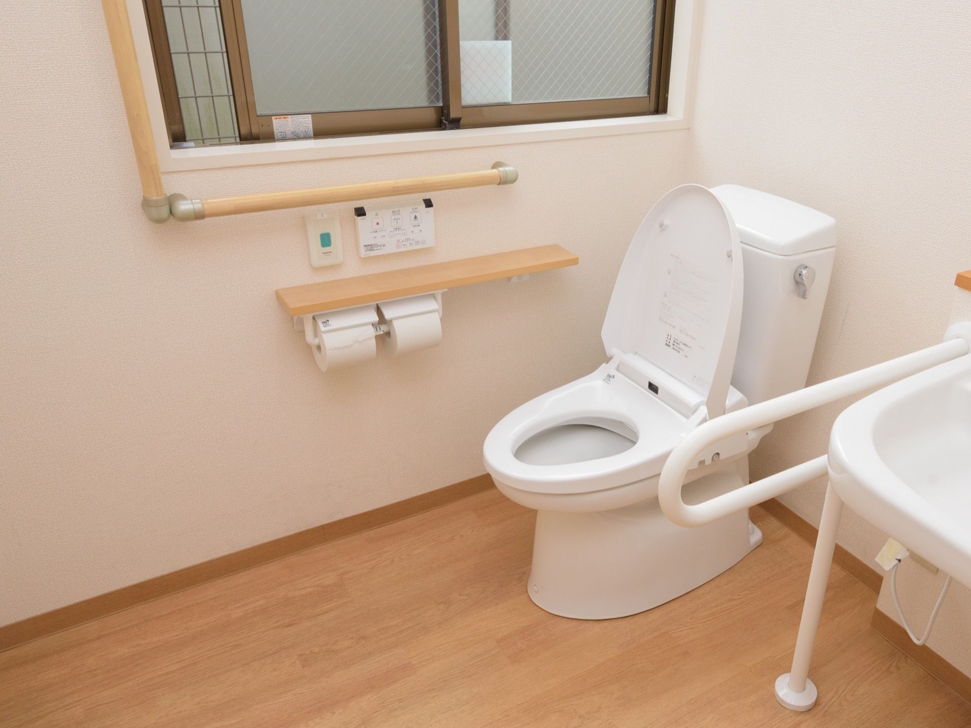 トイレには、洗面台が便器のすぐ隣に備わっている。窓の下には緊急時呼び出しボタンやリモコンが設置されている。