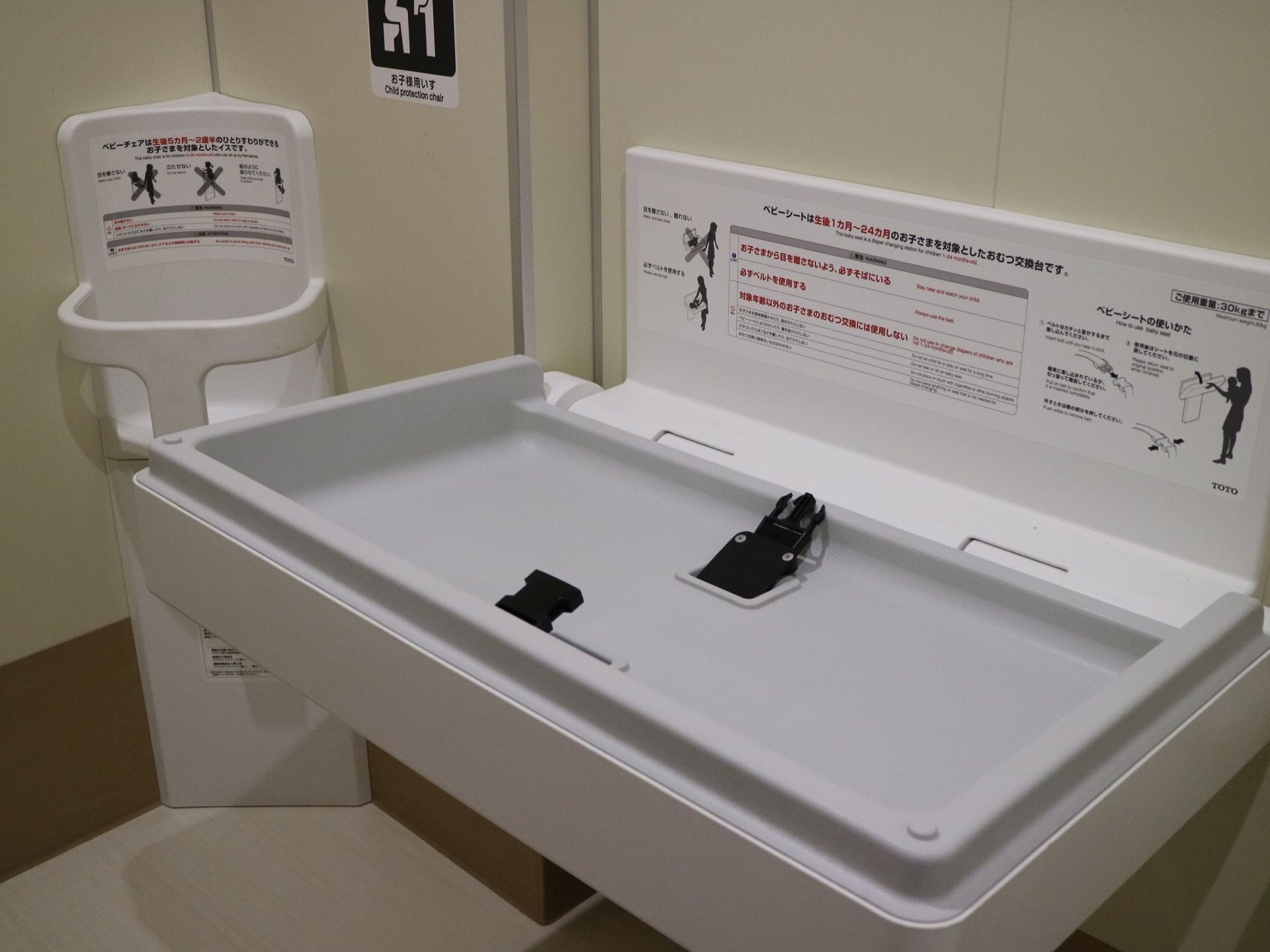 トイレ内にはベビーチェアが設置されている。外すぐ隣にはベビーシートがある。それぞれ説明書きが貼られている。