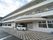 施設は3階建ての建物で、2階以上にはベランダが設けられている。玄関前に施設のロゴが入った軽自動車が止まっている。