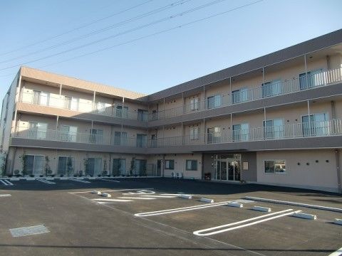 車椅子ご利用の方用の駐車スペースを含む駐車場がある3階建ての施設