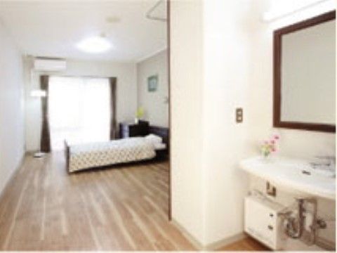 大きな鏡がある広い洗面台、ベッド、チェストがある居室