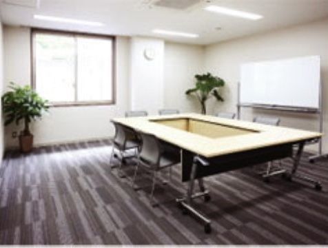 ４人用、１人用２種類のテーブルが並べられた部屋。隅には背の高い観葉植物が置かれている。奥はカーテンがかかっており向こう側がうっすらと見える。