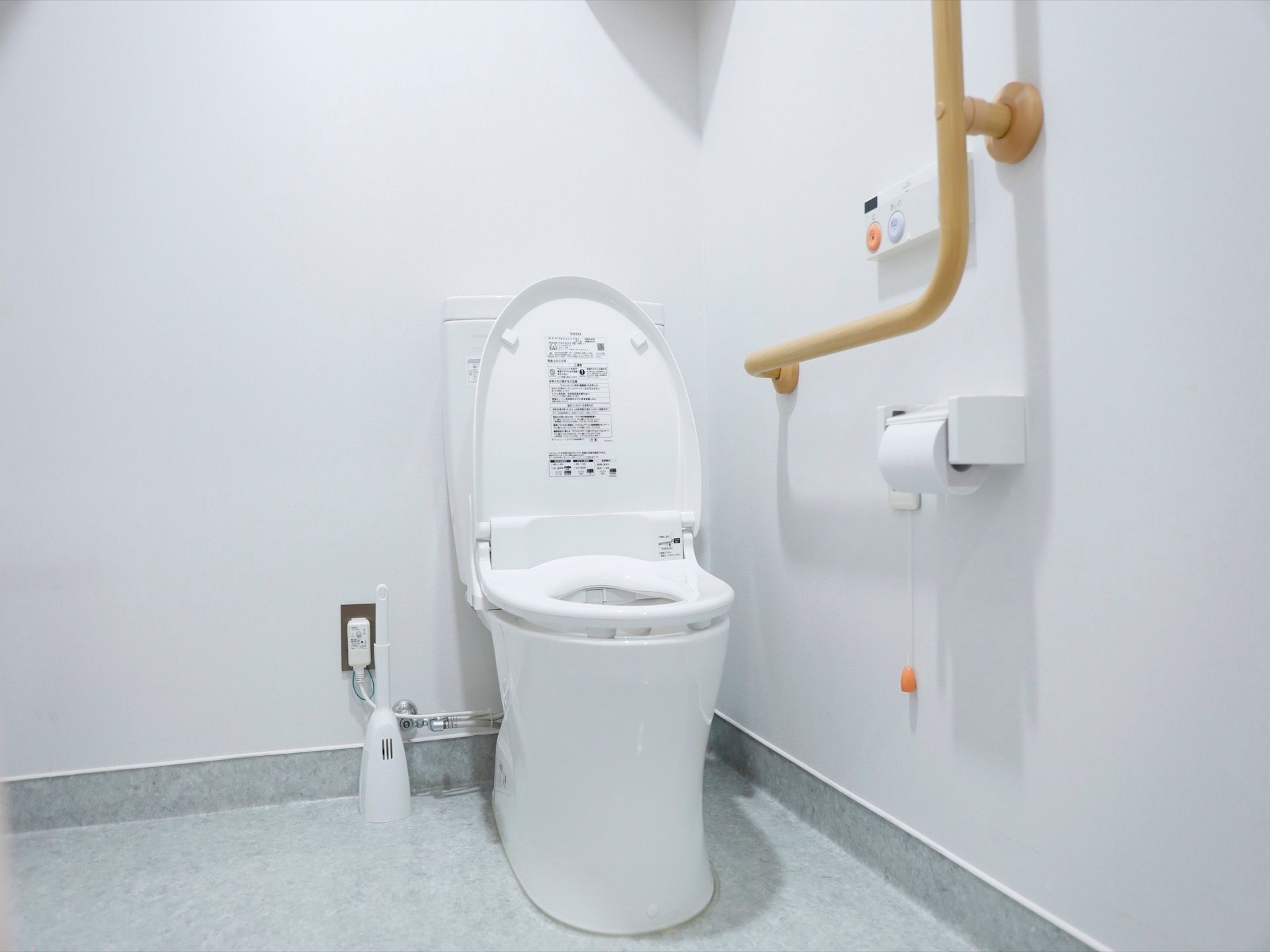 シンプルなトイレである。壁に手すりと呼び出しボタンを設置しており安心である。壁が白く清潔感のあるスペースである。