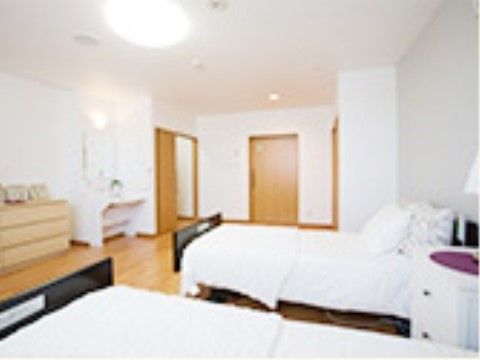 ベッドを２つ置いてもゆったりと使うことができる居室である。タンスや洗面台があり、快適に過ごすことができる。