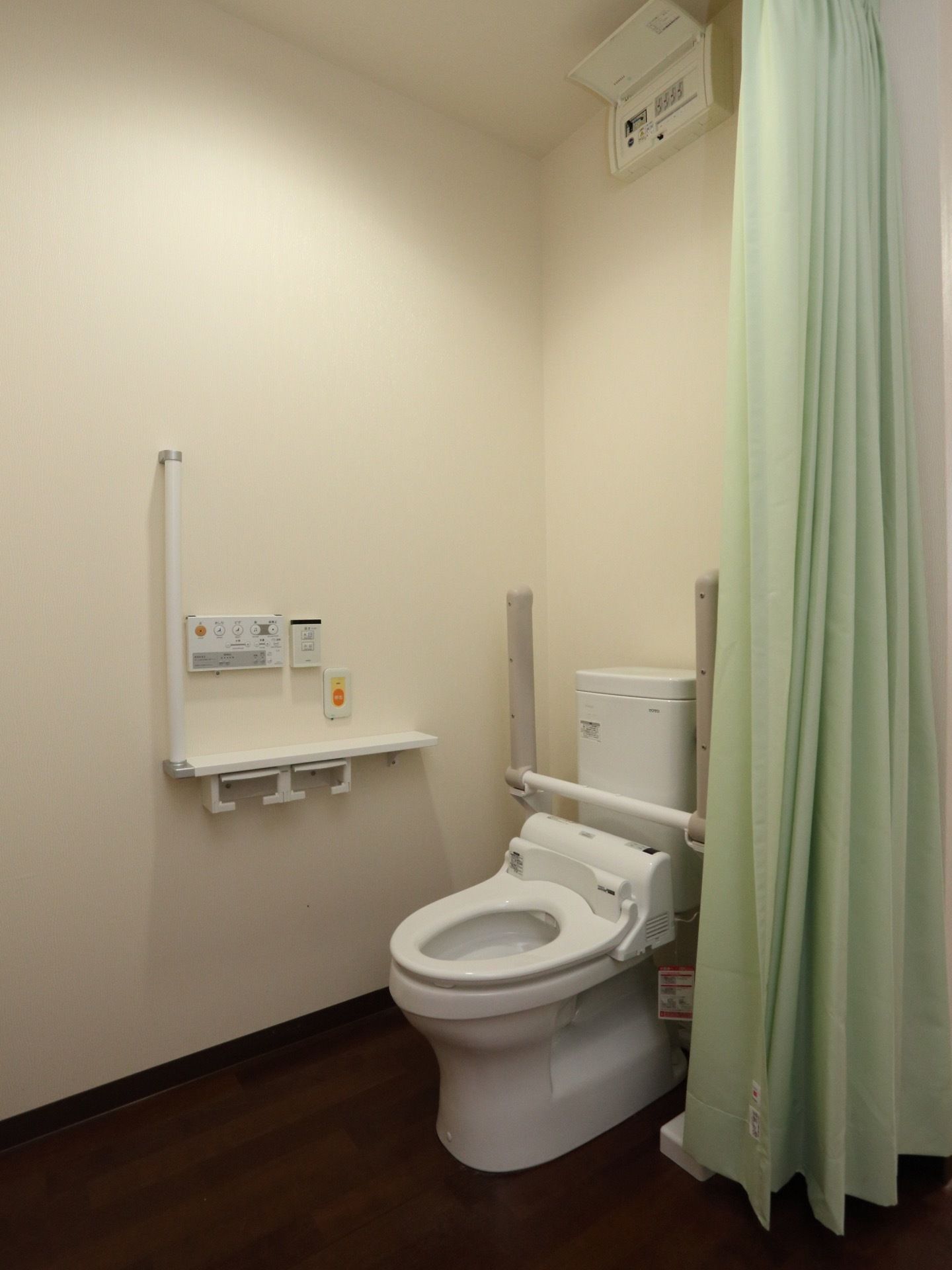 カーテンで仕切られらトイレは、扉の開け閉めがなく利用しやすい。跳ね上げ式の手すりがあり、用途に応じて利用でき便利である。