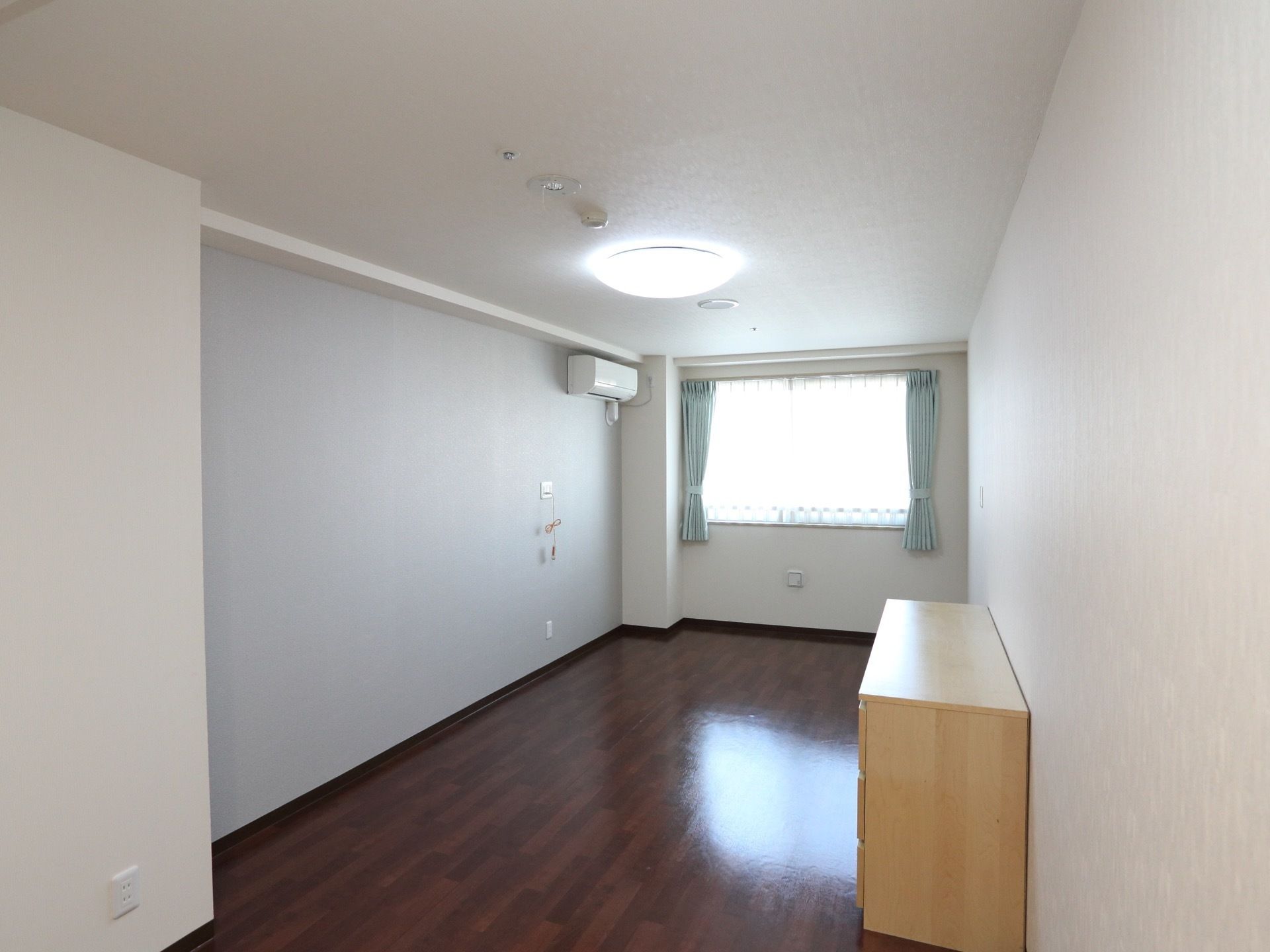 明るい窓際にはエアコンが設置されており、入居者様はリモコンにより自由に室温を設定でき、快適に過ごすことができる。