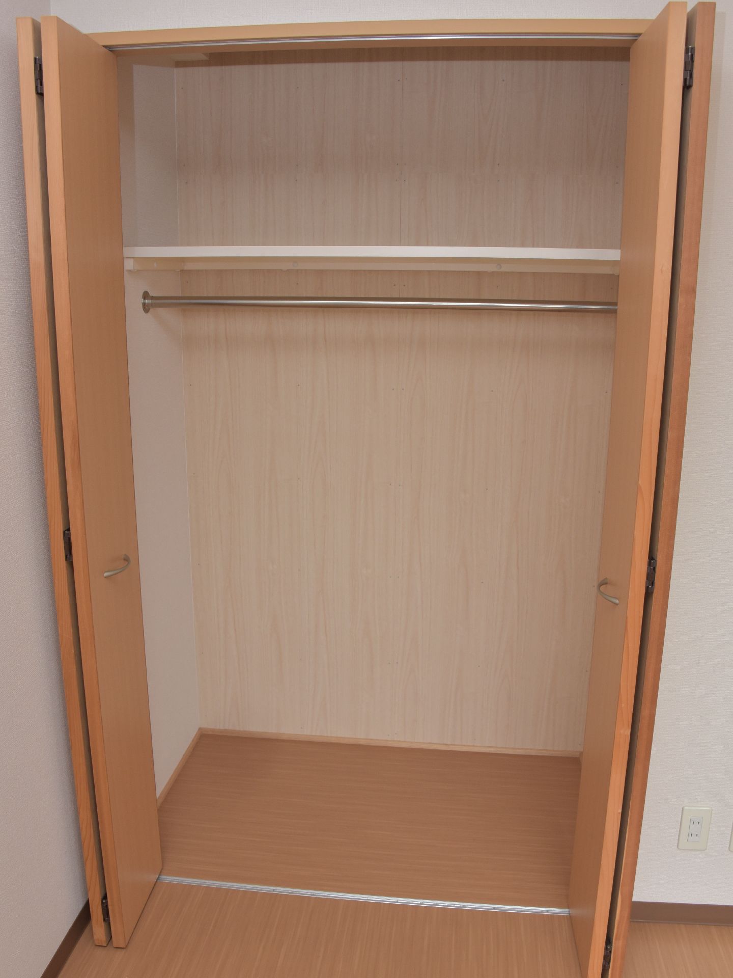 押入れタイプの棚は、レール式の扉になっている。内部は上下に仕切られ、下の部分にはカーテンレールがついて服がかけられるようになっている。
