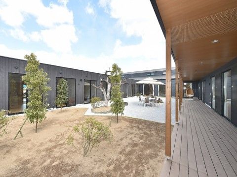 大きな窓に面した居室とパラソル付きのテーブルセットが置かれた中庭