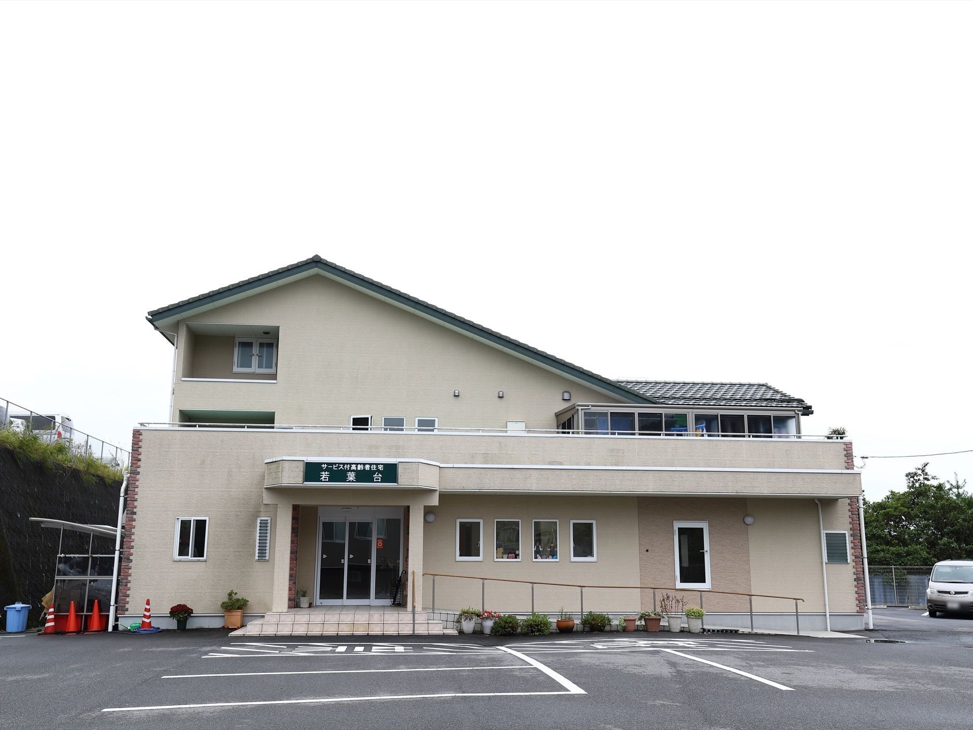 クリーム色の外壁とレンガ、緑色の三角屋根が可愛らしい外観である。入り口前にはスロープも設置され、広い駐車場を備えている。