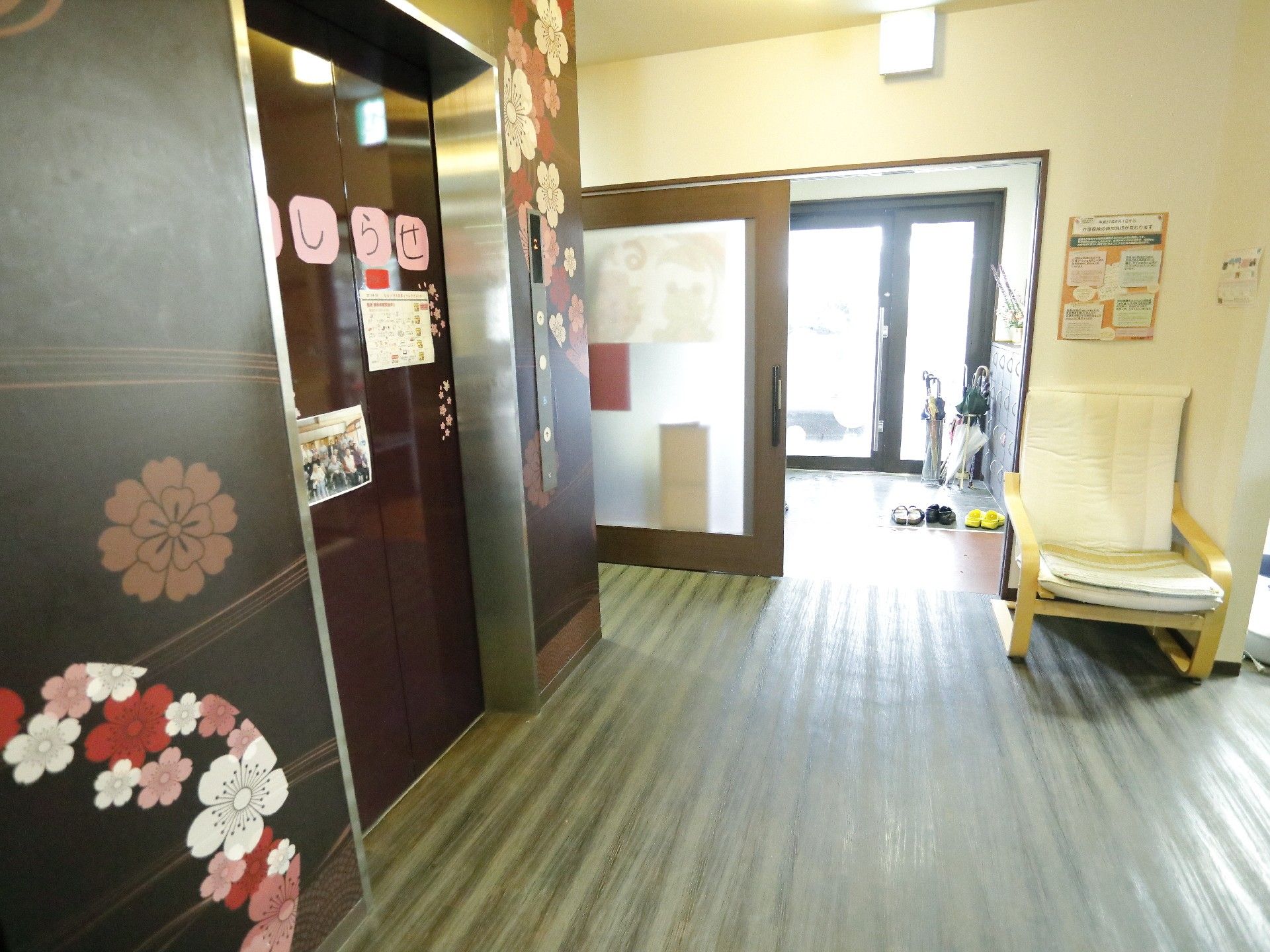椅子でくつろぐ高齢者に微笑みかける女性スタッフ