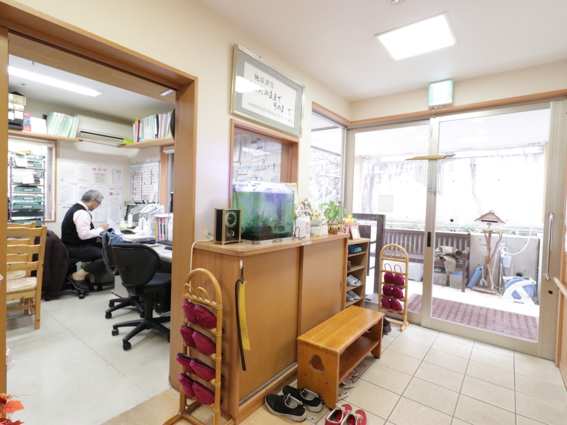 玄関の左側に事務所がある。入居者様やスタッフ用の下駄箱が設置されている。スリッパラックやベンチが置かれている。