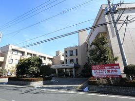 ３階建てである。ベージュ色のマンションタイプの建物である。ショートステイ、デイケアサービス受付中の看板がある。