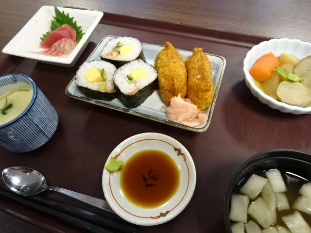 刺身と野菜の煮物と太巻き寿司といなり寿司のセット