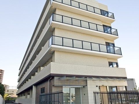 外囲壁にオフホワイトのタイルが施された、5階建ての建物