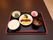 黒いトレーの上に1人分の食事メニューがセットされている。ご飯と味噌汁のほか、主菜と副菜が彩りよく並んでいる。