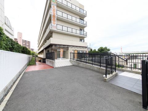 施設の玄関前には4段のステップがある。右側にはスロープがあり、両脇には手すり付きのフェンスが設置されている。