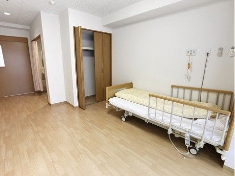 介護用ベッドが設置されたフローリングの床の個室部屋