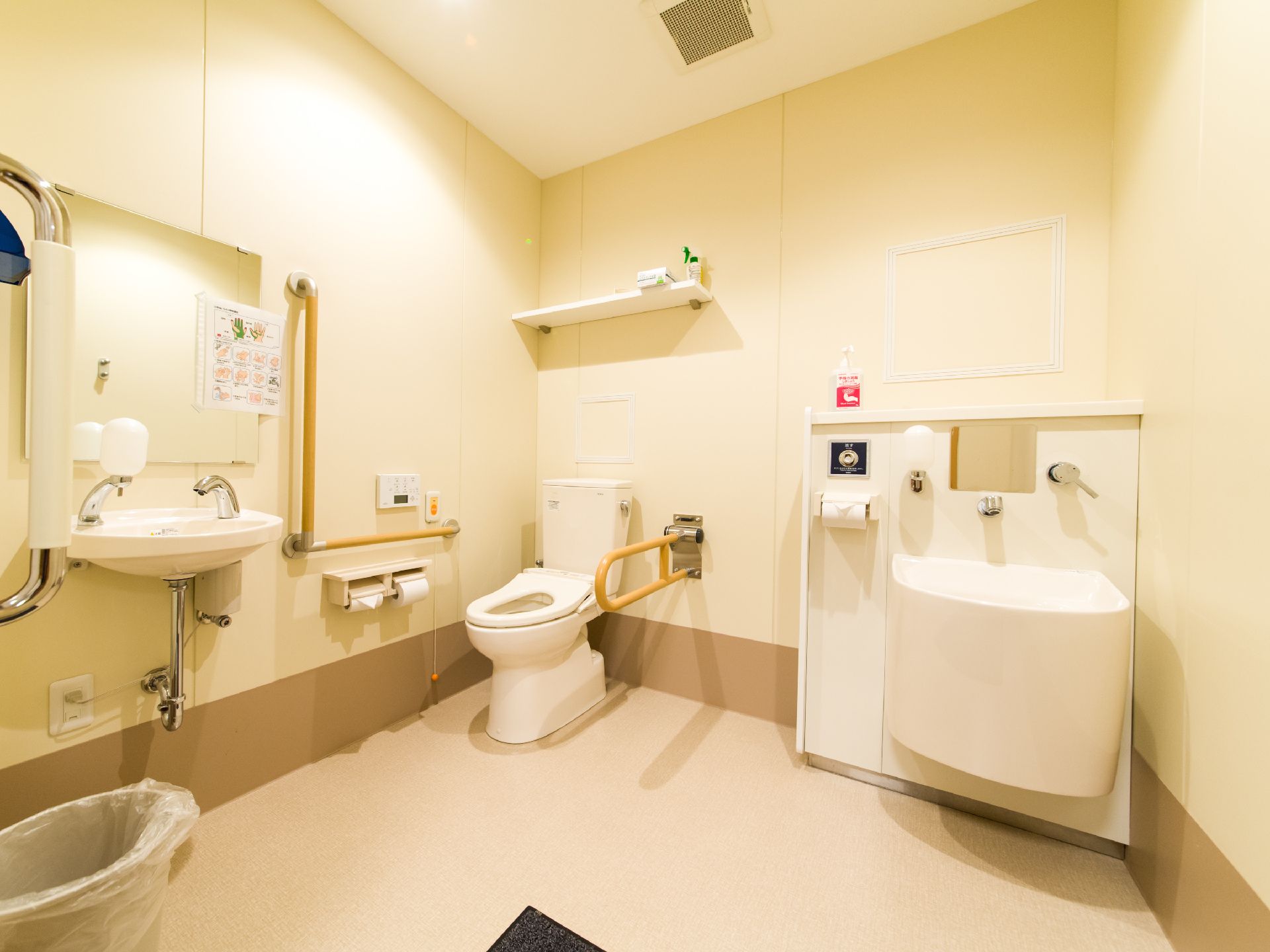 広くなっているトイレルームの奥に便座がある。天井には物を置くスペースがあり、その横部分と、手前の2ヶ所に手洗い場が見える。