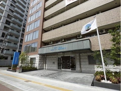 鉄骨造で重厚感のある高層階建ての施設建物と施設の入り口