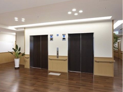 落ち着いた色合いの配色のホールには、観葉植物が設置されている。また広いスペースに手すりも設置されているため、安全面に配慮されている。