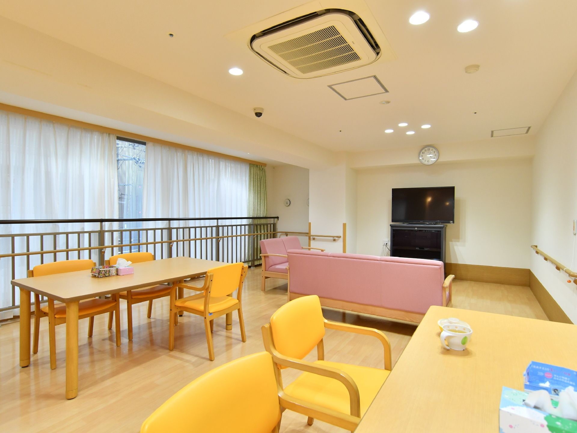 複数のテーブルがあり、その上にはティシュが置かれている。天井にはエアコンが設置されている。壁は白色になっている。