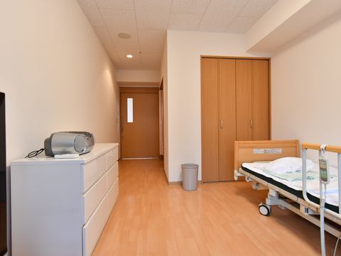 リクライニングベッドと収納棚とオーディオ機器が配置された個室部屋