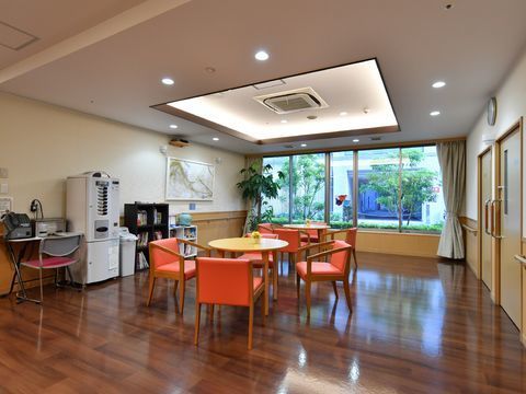 正面と奥には丸テーブルがあり、周囲にはオレンジ色の椅子が置かれている。左側には電話機が設置されている。