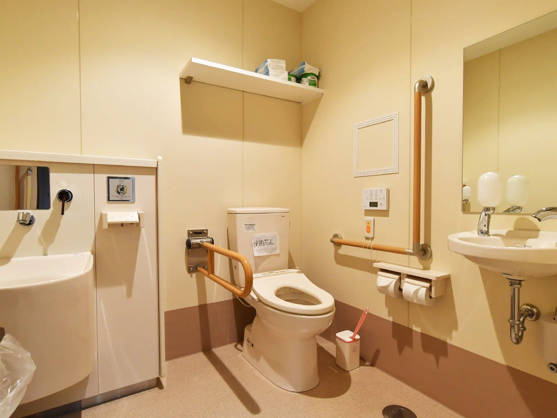 右側には便器がある。その左側には可動式の手すりがあり、右側にはL字型のものが付いている。右壁には緊急呼び出し装置がある。