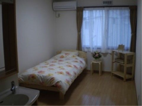 シングルベッドとエアコンが設置された施設の一人用の個室