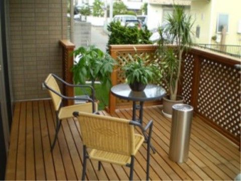 ウッドデッキは観葉植物が飾られた憩いの場となっている。アンティーク調の円型テーブルと椅子、灰皿が設置されている。