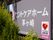 看板には、グレー色の背景に白い字で施設名が大きく表示されている。右下には、AEDを完備している施設であることを示すシールが貼ってある。