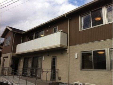 茶色をベースとした外壁で玄関近くには手すりが設けられている施設建物
