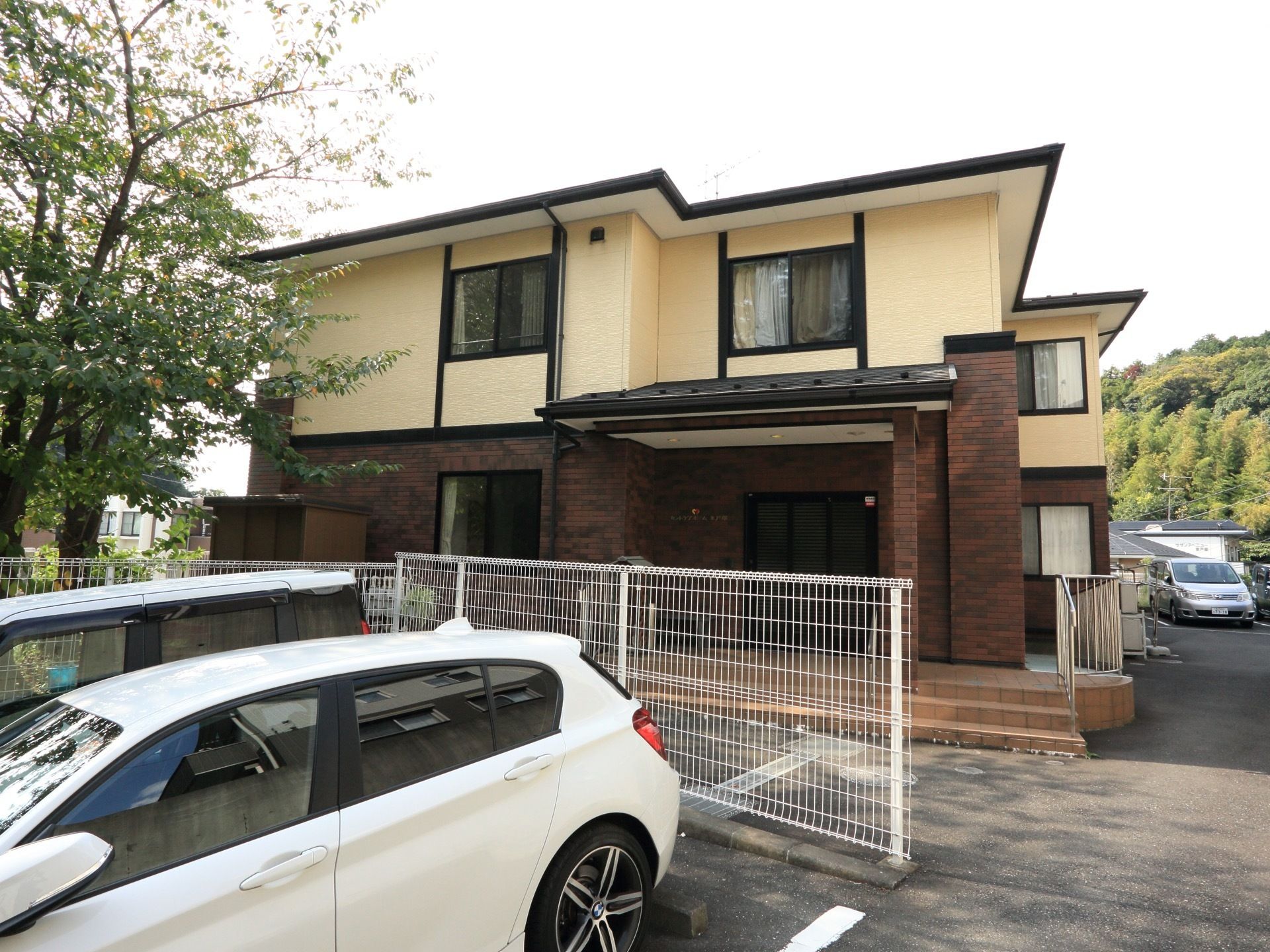 施設の前には、専用駐車場がある。駐車場から玄関までは、とても近くて便利である。後ろには金網の柵がある。