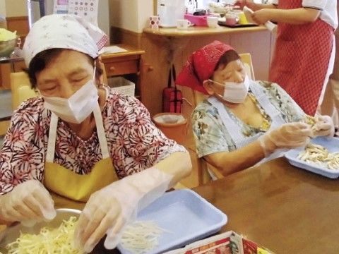 施設内にて料理の手伝いをしている女性のご入居者様二名の姿