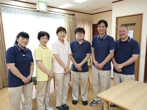 施設の制服を着て一列に並んでいる、笑顔の施設スタッフ達