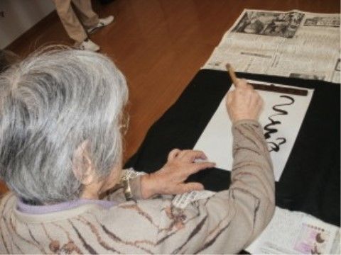 施設内にて書道を楽しんでいる、女性のご入居者様の姿
