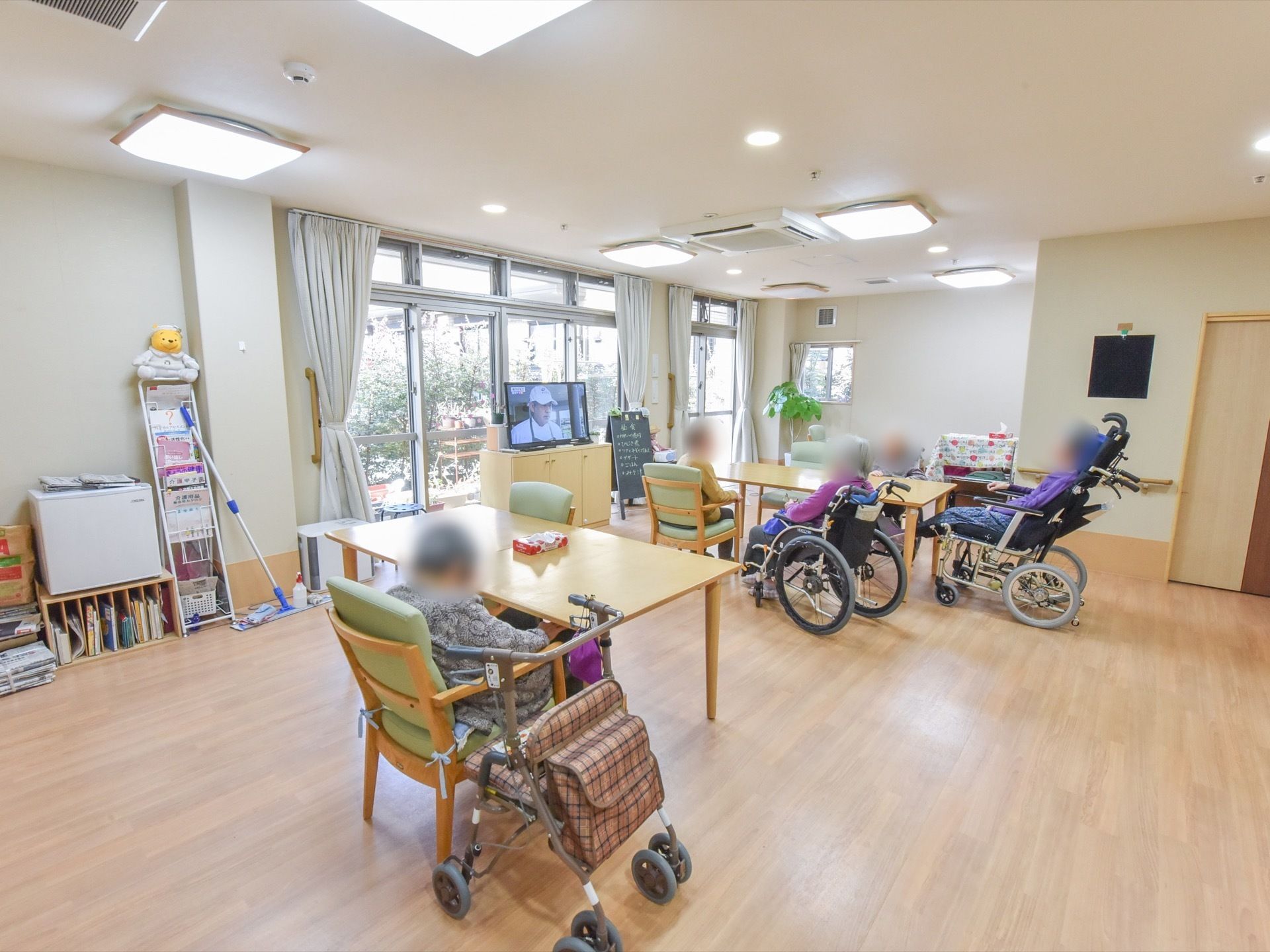庭が見える大きい窓があるリビングルームには、共有のテレビがある。入居者様はテレビを鑑賞して過ごしている。