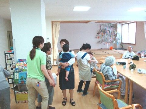 奥に七夕飾りがある共有スペースに、集まって歓談している入居者たち